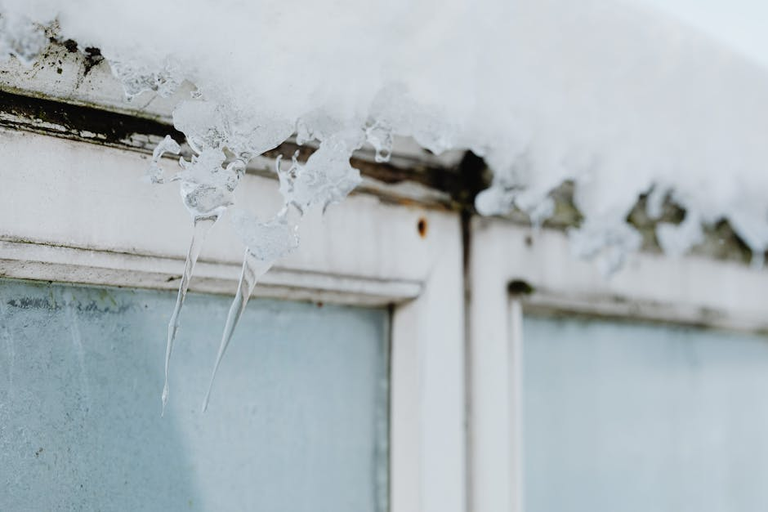 Icicles hanging above a window in winter — draught proofing and sealing gaps dramatically reduces heat loss and heating bills